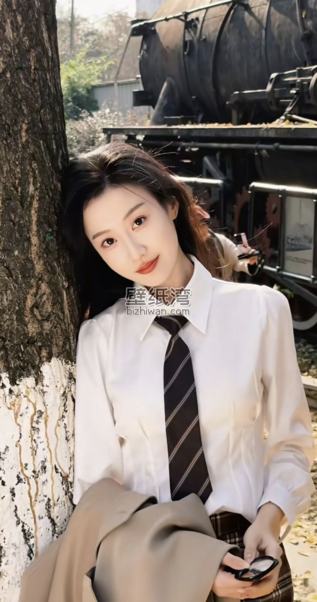 女生穿着白色衬衫和领带，倚靠在树旁，身后是废弃的火车，手机壁纸图片