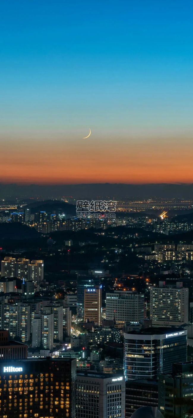 城市夜景与新月，远处山脉轮廓清晰