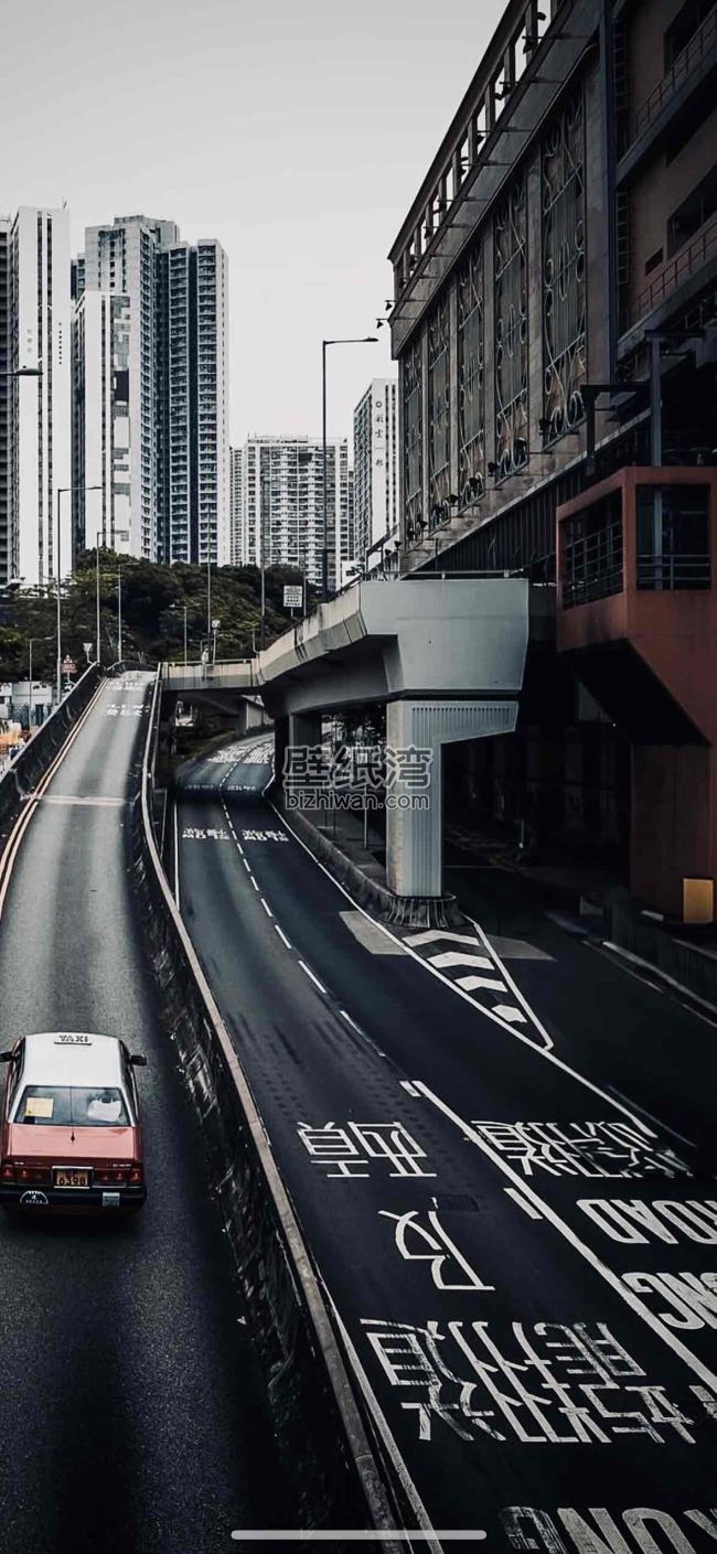 城市高架桥下的道路，两侧高楼林立，红色出租车行驶在道路上,手机壁纸