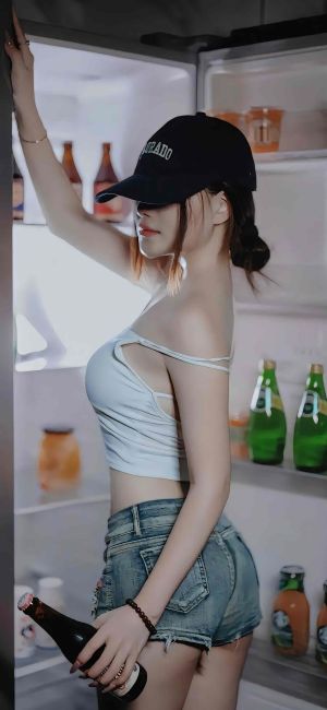 美女在冰箱前手持啤酒瓶，穿着露脐上衣和牛仔短裤