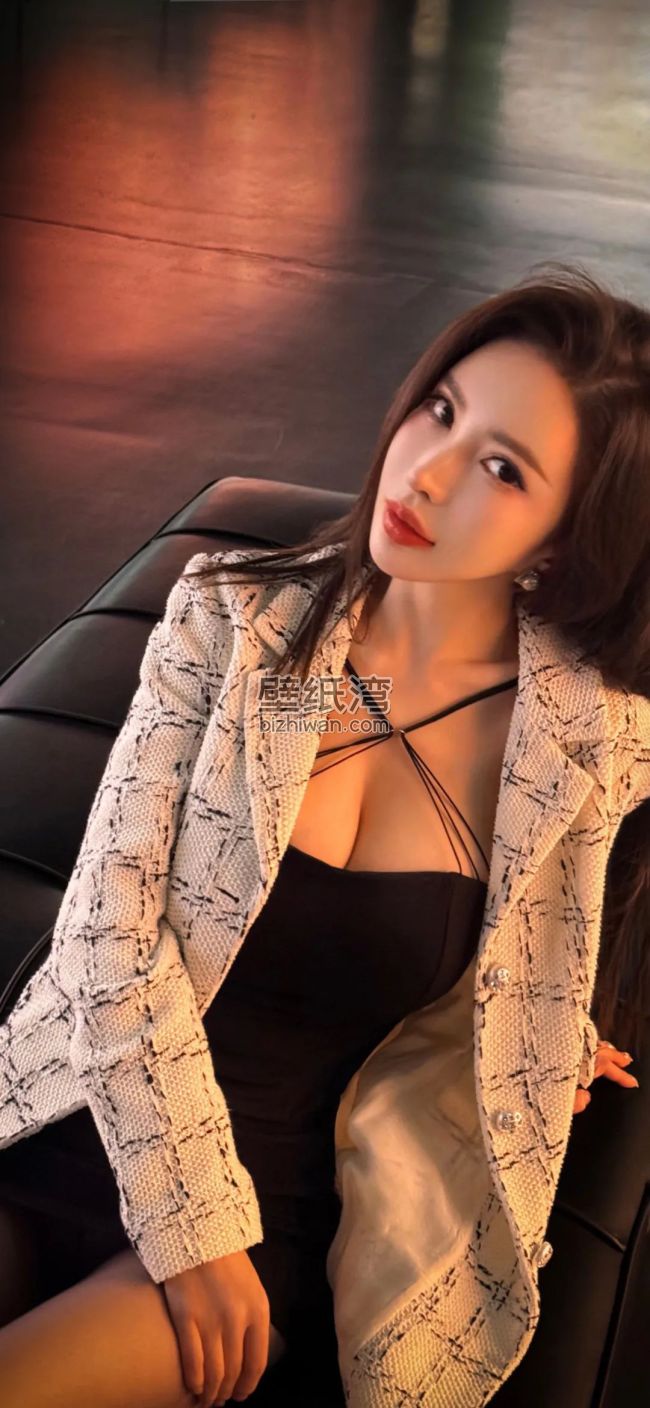 性感时尚美女穿着黑白格纹外套和黑色连衣裙坐在沙发上 手机壁纸