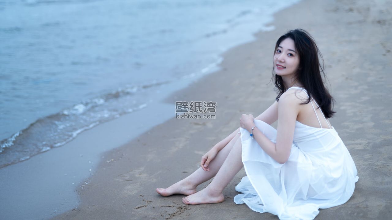 穿着白色连衣裙的美女坐在沙滩上，平静的海面