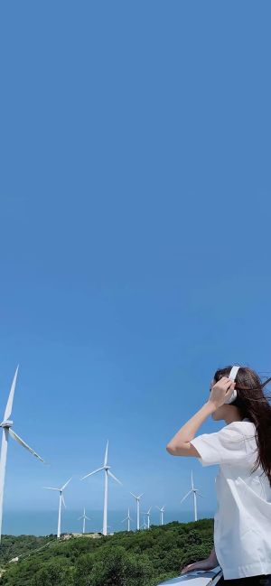 青春美女在风力发电场拍照，蓝天和绿色山丘