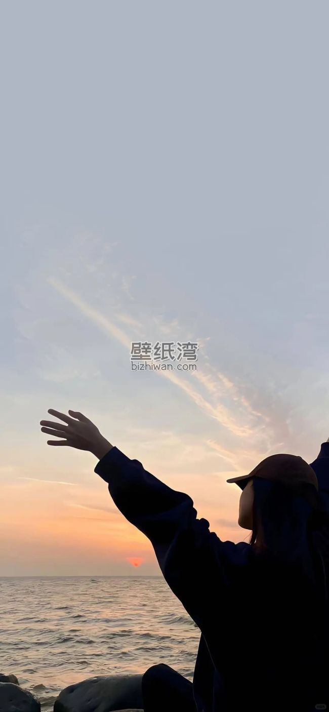海边日落时分，女孩伸出手臂仰望天空